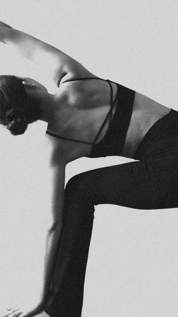 Una mujer sostiene un estiramiento largo, con el cuerpo en tension.